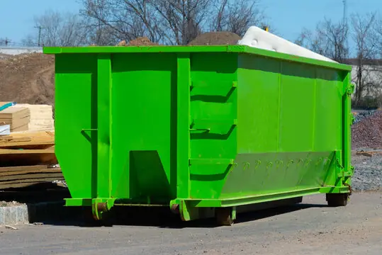 Roll-off dumpster loaded with roofing and building debris